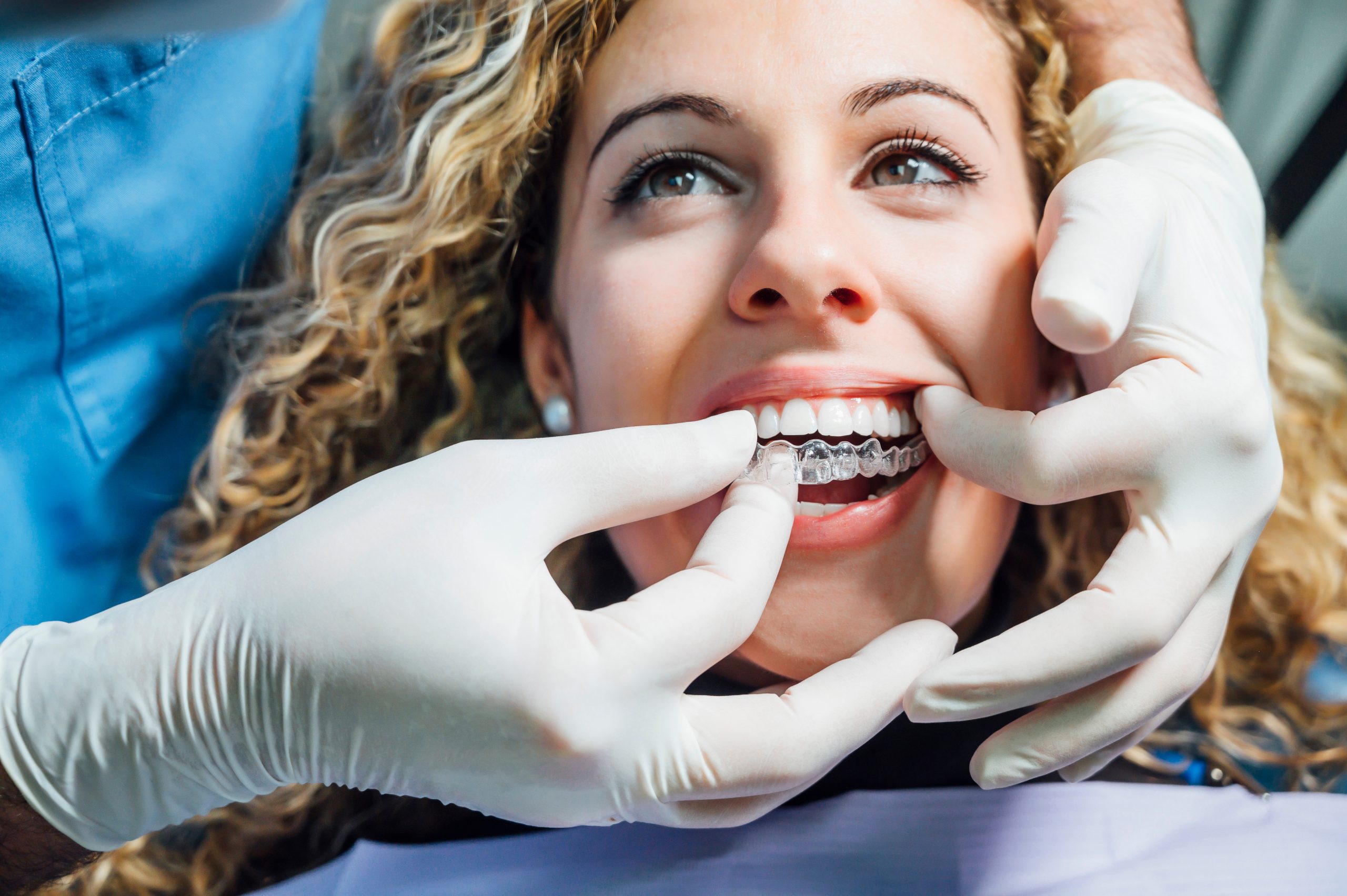 Doctor putting clear dental aligner to the patient woman